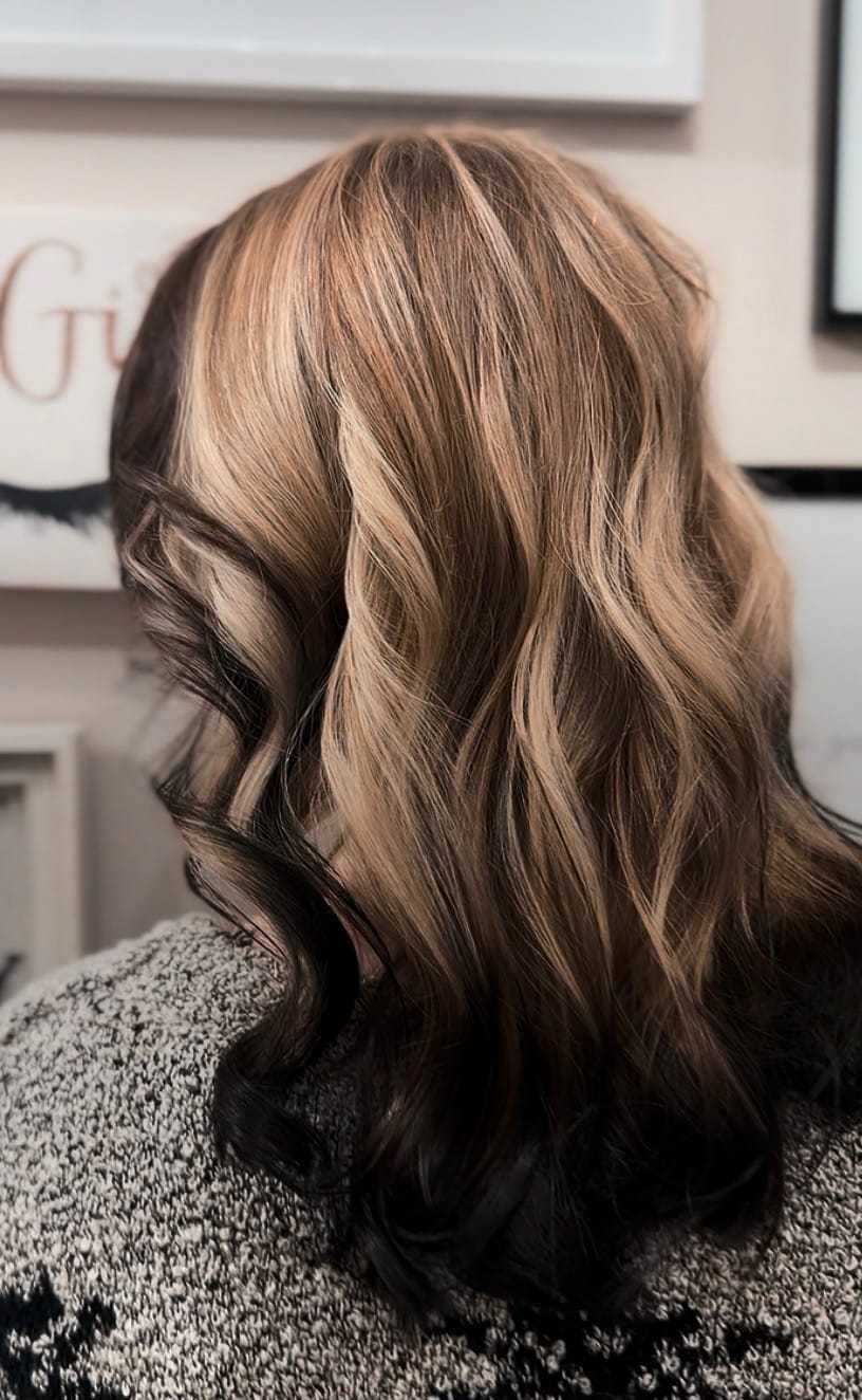 Wavy hair with blonde highlights on display in a salon setting.