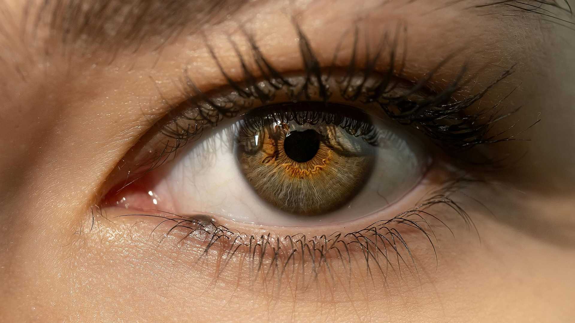 Close-up of a human eye with detailed iris patterns and long eyelashes visible.