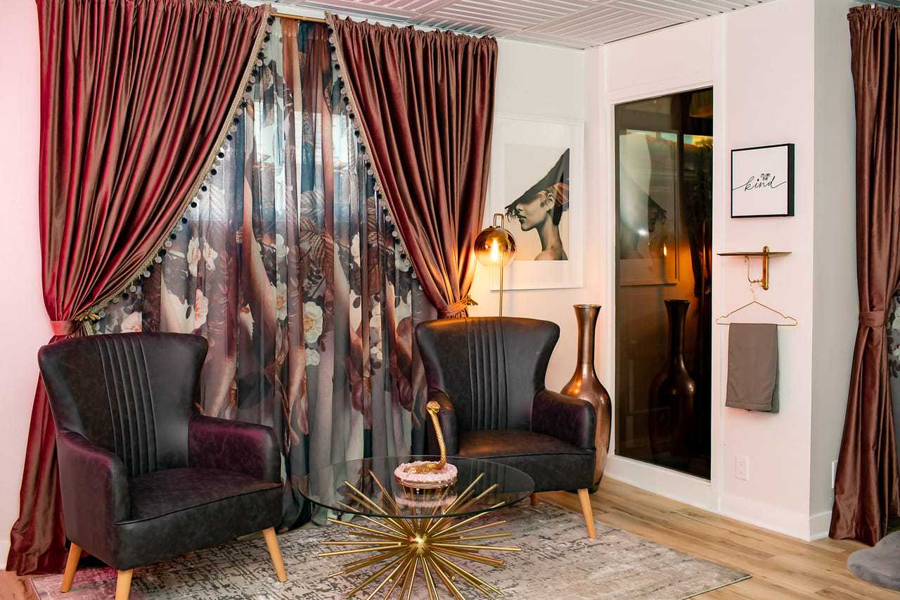 Elegant living room with armchairs, floral curtains, and modern decor features.