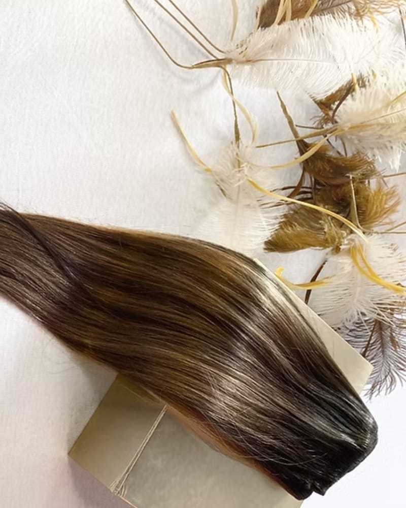 Strand of brown hair next to a box and decorative feathers.