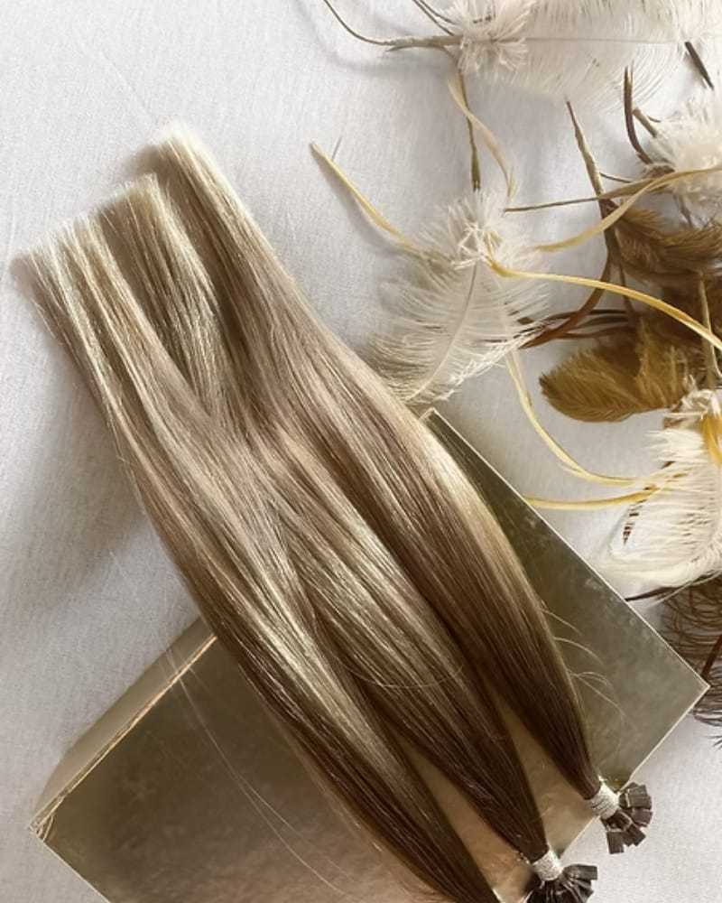 Blonde hair extensions on a gold box with decorative feathers nearby.