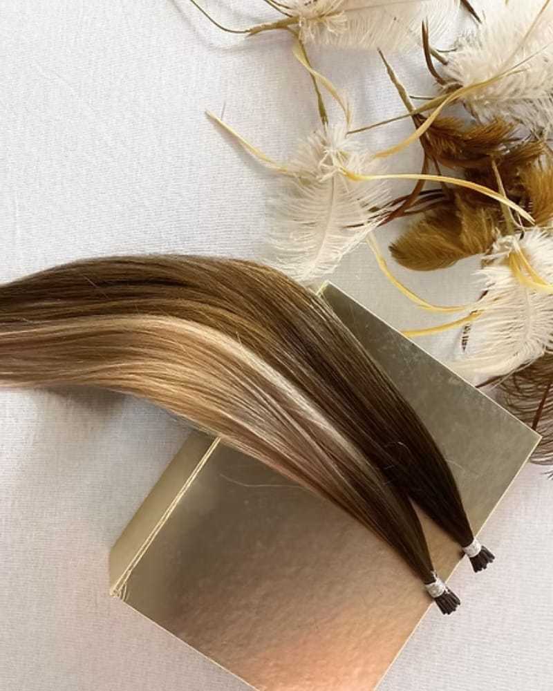 Braided brown and blonde hair extension on a gold box with decorative feathers.